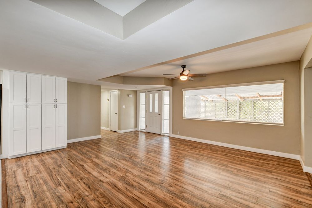 Newly painted rental home interior with wood-look flooring, built-in cabinets, and large windows